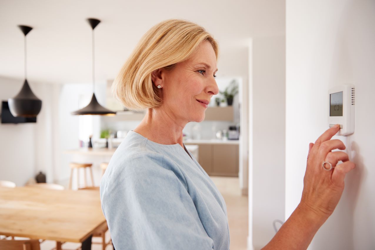 Photo of woman adjusting thermostat on her Missoula, Montana HVAC system